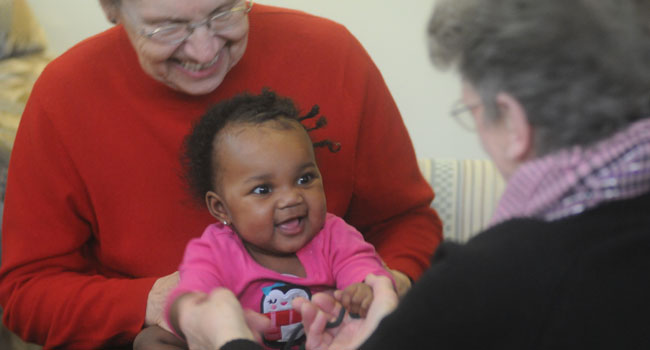 Sisters play with a baby at Theresa Living Center in Minneapolis.