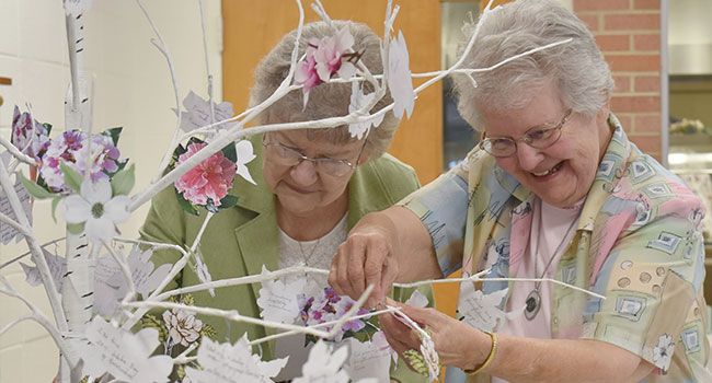 Sisters Ancilla Roussel and Lorraine Landry hang their reflections on a tree at A Celebration of Gratitude and Farewell to 145 Years of SSND Presence in Chatawa, Mississippi, in September 2019.