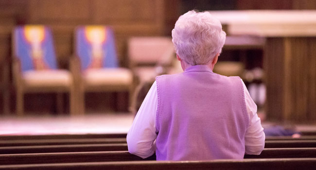 A picture of a women praying in a church.