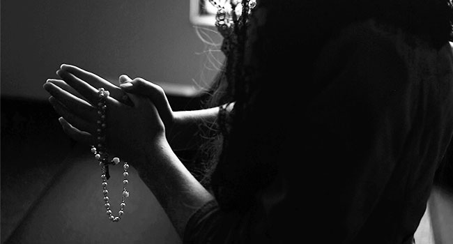 This photo is of a young women praying in black and white. The photo is being used for the article covering Lent and COVID-19.