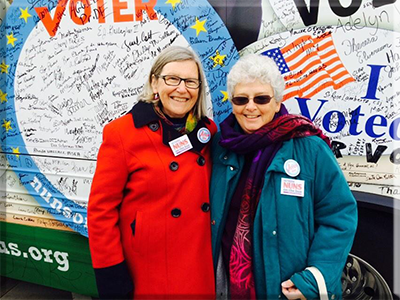 Sister Simone Campbell, SSS, executive director of NETWORK and Sister Barbara Pfarr, SSND stand in front of the bus during the Nuns on the Bus “We the People, We the Voters” tour extension in Wisconsin.