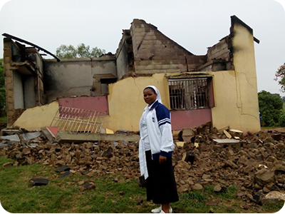 Sister Joyce Nyakwama in front of destroyed hostel