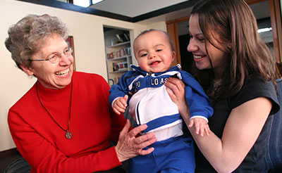 Sister Rita Jirik interating with a mother and child at the Theresa Living Center in St. Paul, Minnesota. 