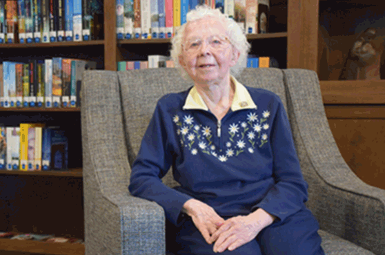 Sister Jacqueline Buckley seated in the library at Trinity Woods.