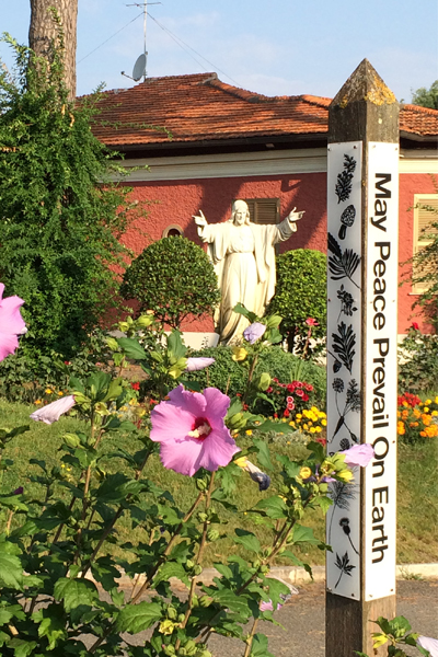 This photo is of a Peace Pole and a statue of Jesus. 