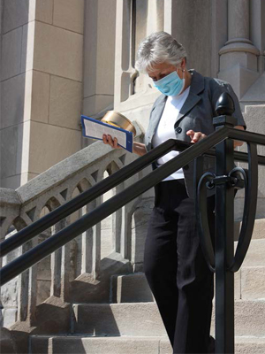 Sister Janice Munier is the first Parish Life Coordinator for the St. Louis Archdiocese. She can be seen wearing a mask on the church front steps.